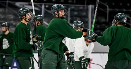 Minnesota Wild top prospect Charlie Stramel, center, bumps fists with Ryker Lee during hockey practice on Thursday, Sept. 25, 2025, at Munn Arena in East Lansing.